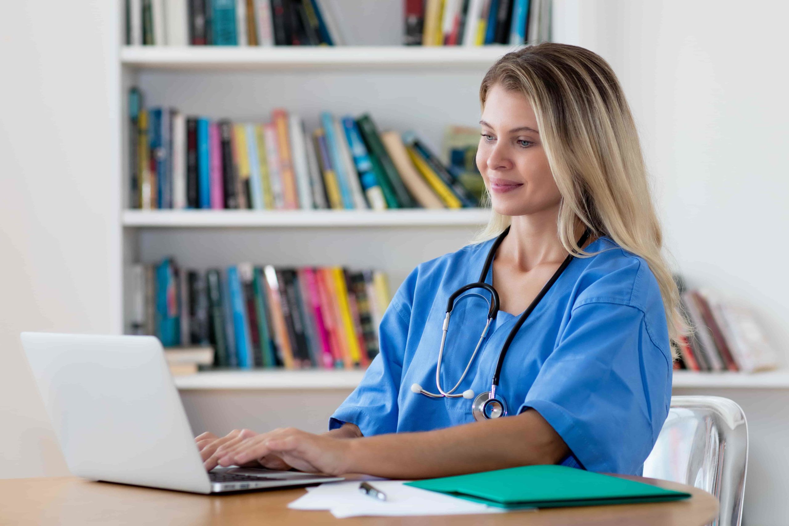 A blonde medical professional using a laptop